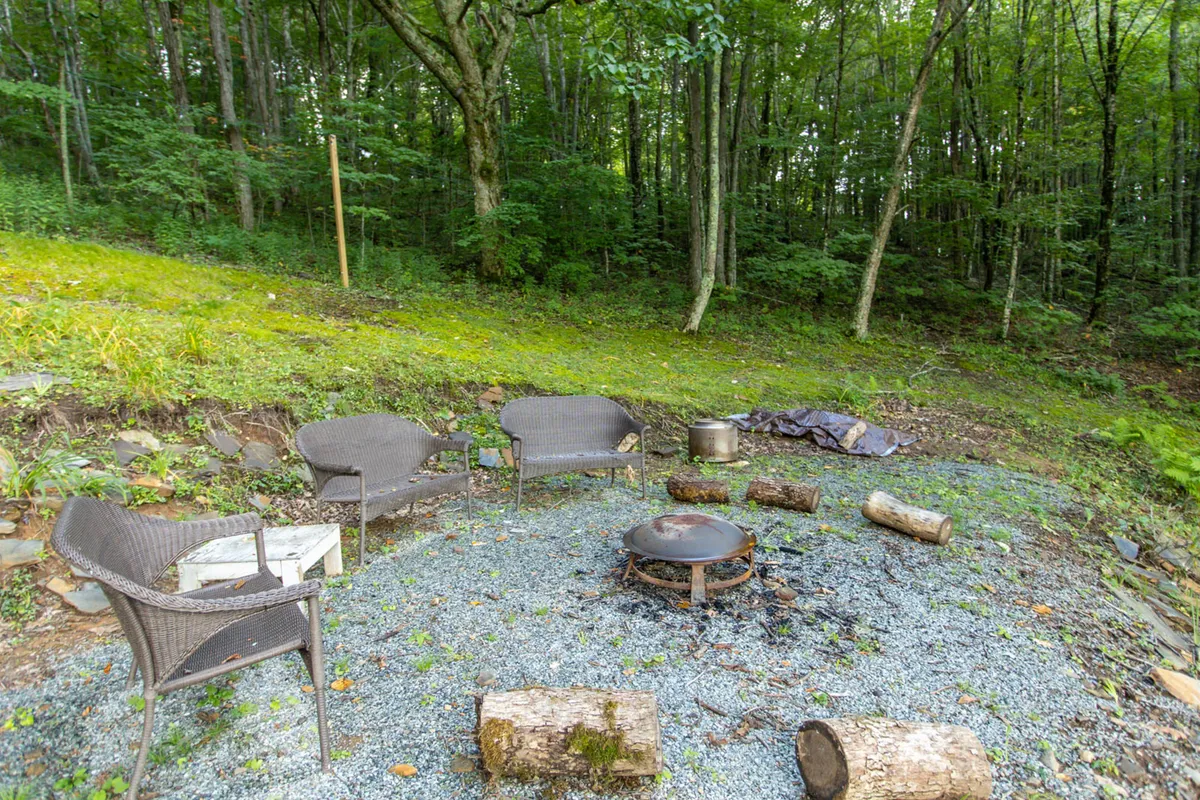 A cozy firepit area surrounded by lush greenery, with comfortable seating arranged around a crackling campfire. The atmosphere invites guests to gather for storytelling, roasting marshmallows, and stargazing under the open sky—a perfect spot to connect with nature and each other.